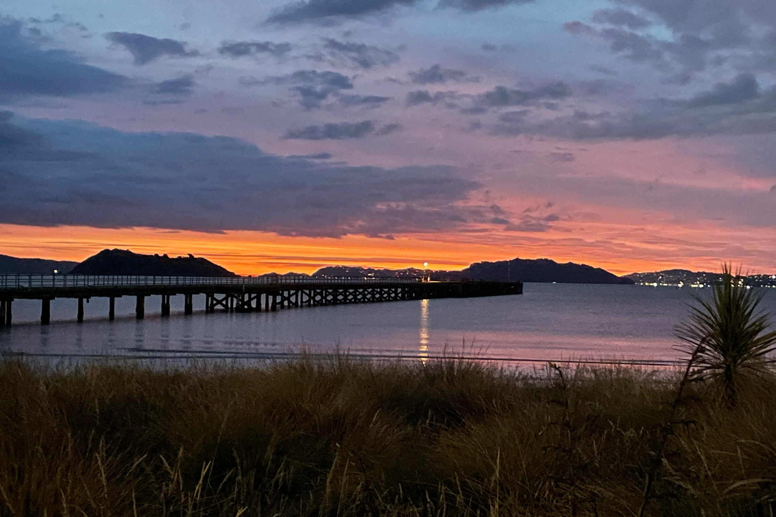 Sunset over Petone Beach, Wellington with orange and pink sky reflecting on calm water