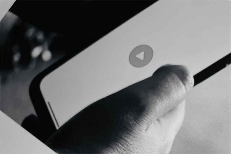 Person looks at their phone with a play button visible